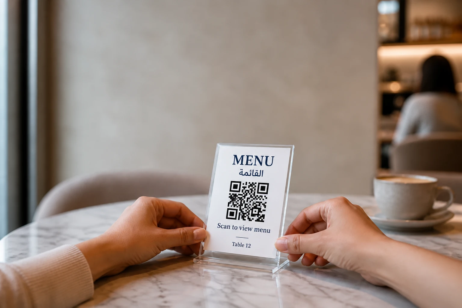 Hands placing a small QR code table stand onto a marble cafe table.