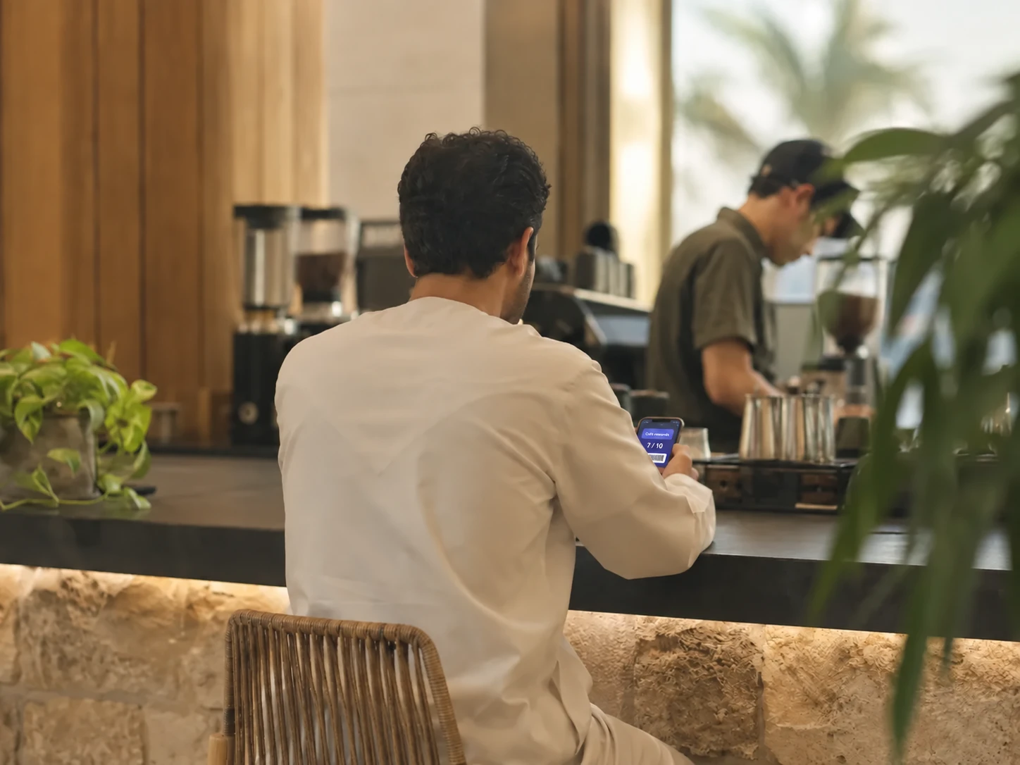 A regular customer at a neighbourhood cafe counter, holding a phone.