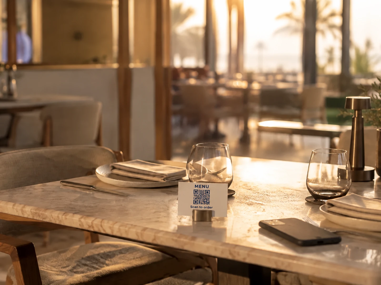 A dressed restaurant table at golden hour with a small card holder standing on it.